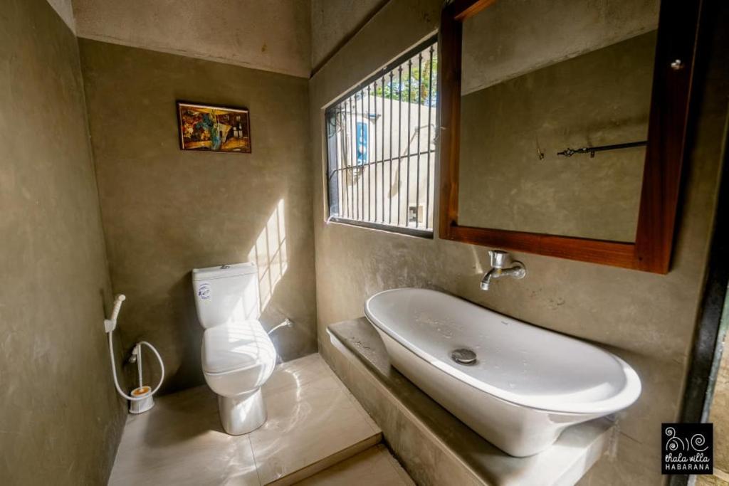 Un baño con lavabo, inodoro y ventana. en Thaala Villa - Habarana, en Habarana