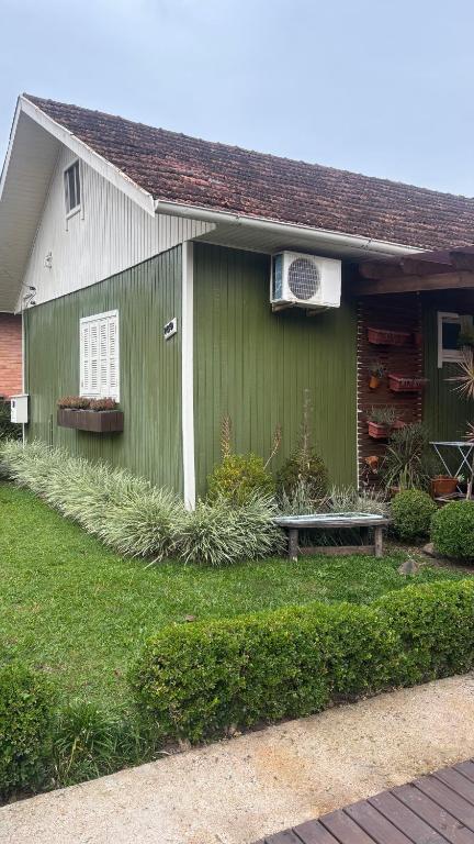 a green house with a bench in front of it at Morada da Floresta in Gramado