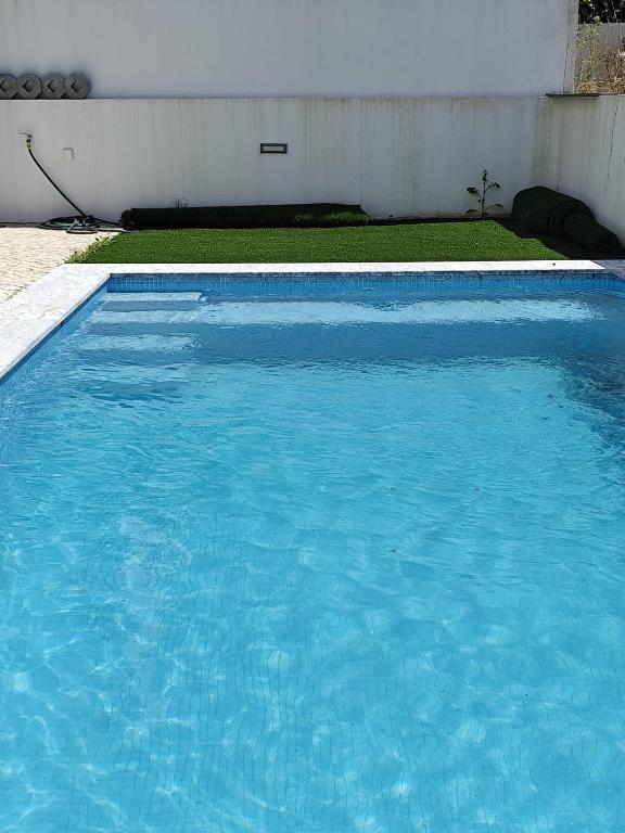 a large pool of blue water in a yard at Casa Alto das Vinhas in Sesimbra
