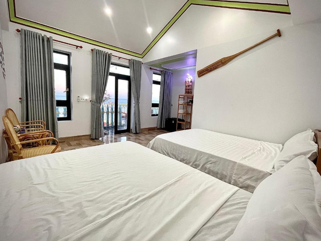 Phú HiệpにあるBien Xanh Homestayのベッドルーム1室(白いベッド2台、窓付)