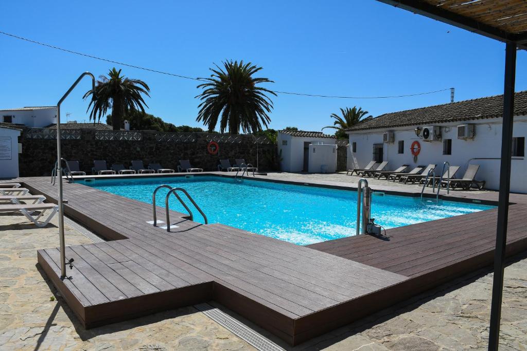 ein Schwimmbad mit Holzterrasse neben einem Gebäude in der Unterkunft La Codorniz in Tarifa