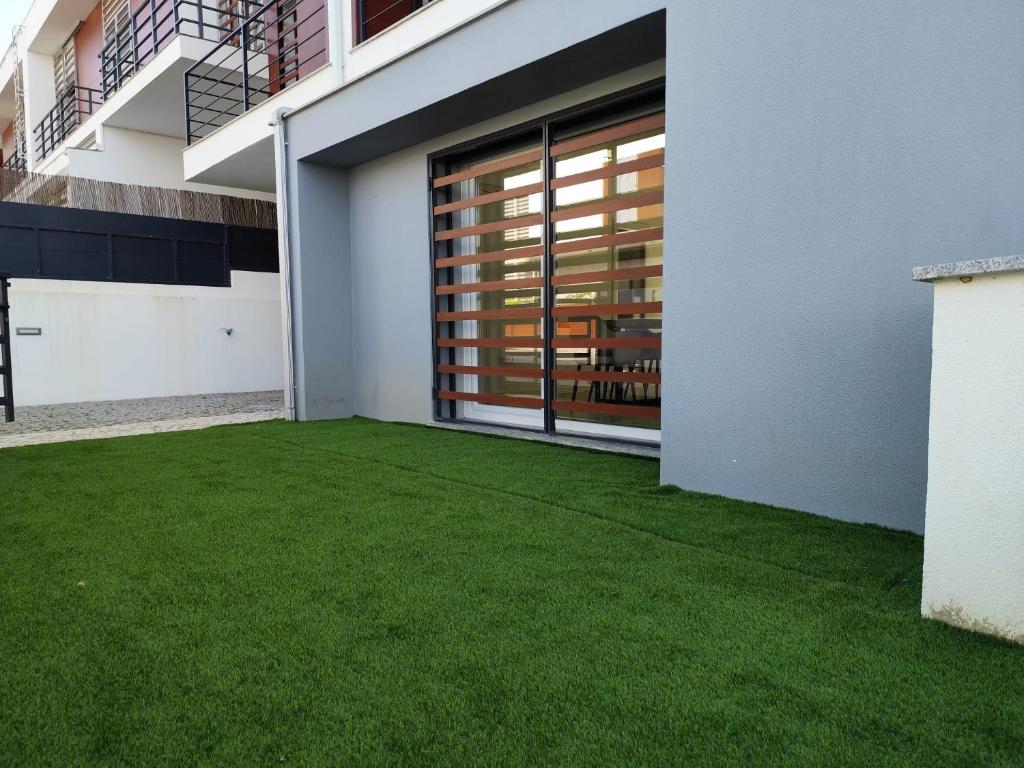 un patio avec de l'herbe verte à côté d'un bâtiment dans l'établissement Casa Alto das Vinhas, à Sesimbra