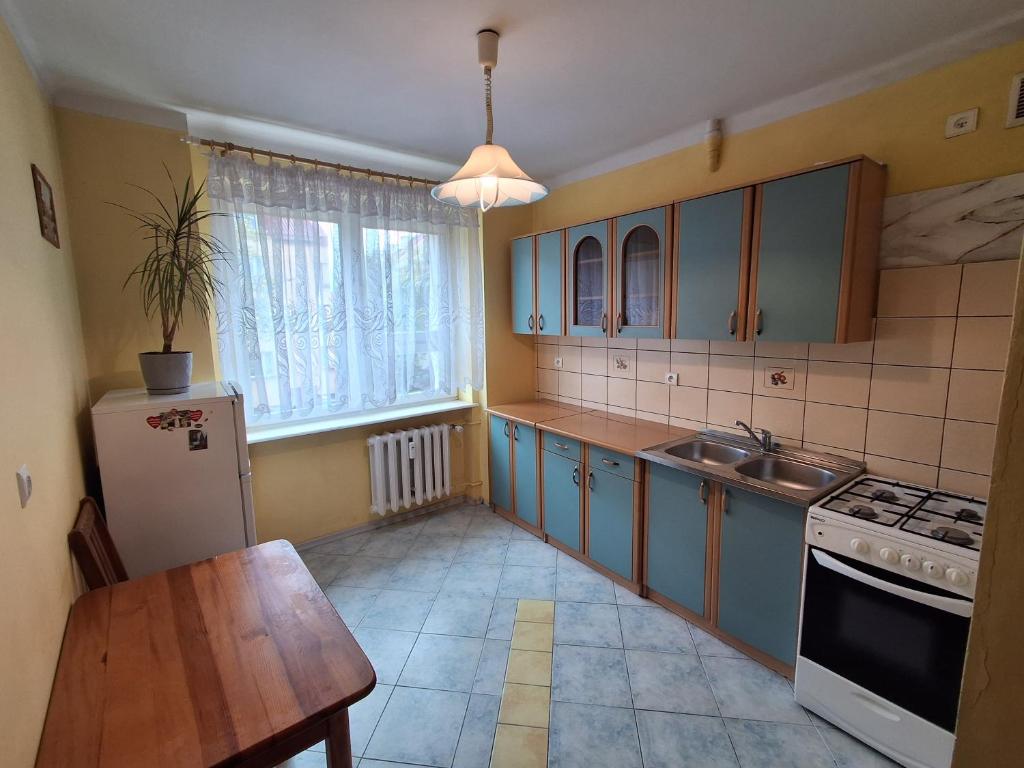 a kitchen with blue cabinets and a table and a refrigerator at Mieszkanie w centrum blisko jeziora in Ostróda