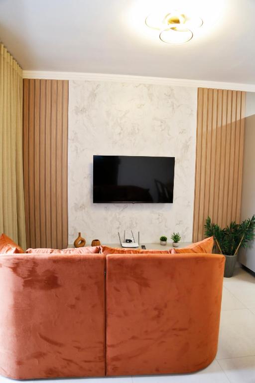 a living room with a couch and a tv on a wall at Comforto e tranquilidade in Franca