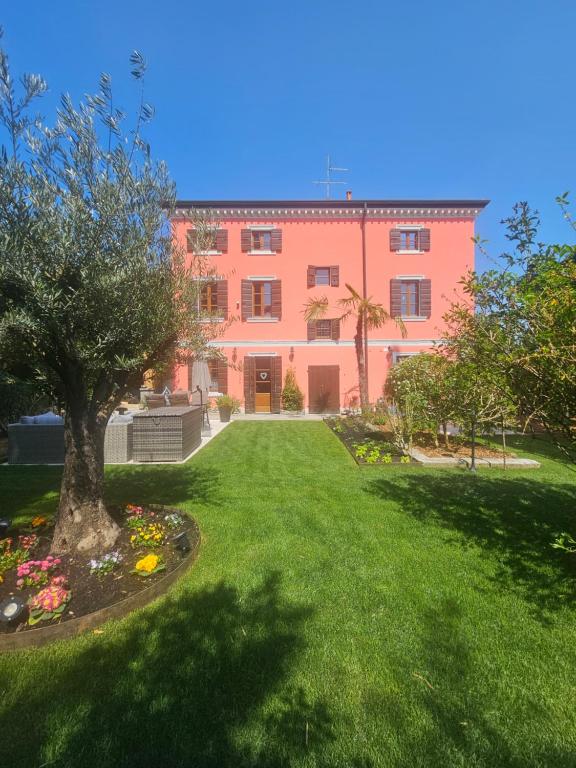 un grand bâtiment rose avec une cour verdoyante dans l'établissement Residence Katrins, à San Giorgio in Salici