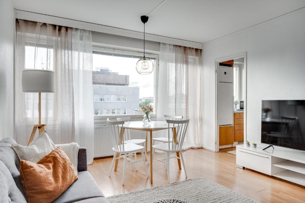a living room with a table and a dining room at SELF-SERVICE penthouse studio in the heart of Turku! in Turku