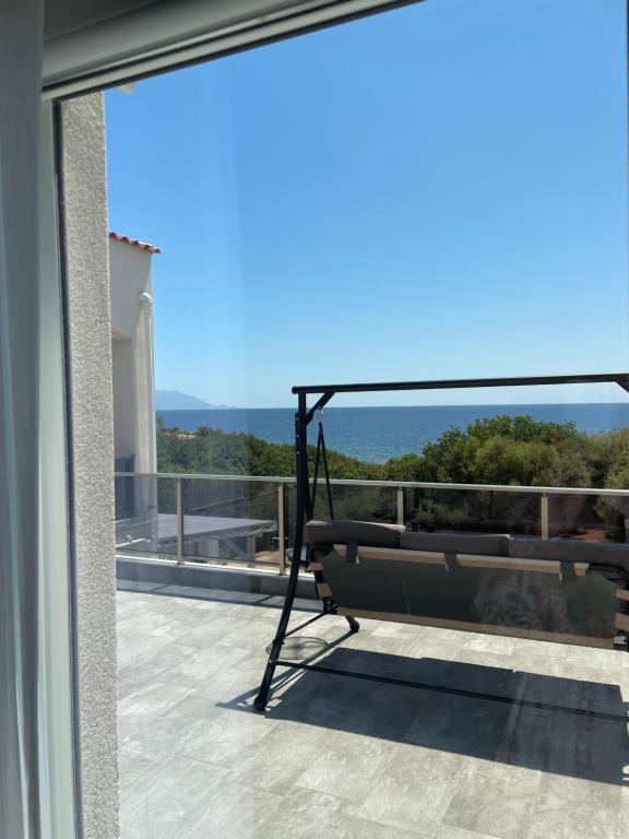 a balcony with a bench and a view of the ocean at Platan Paradise in Maronia
