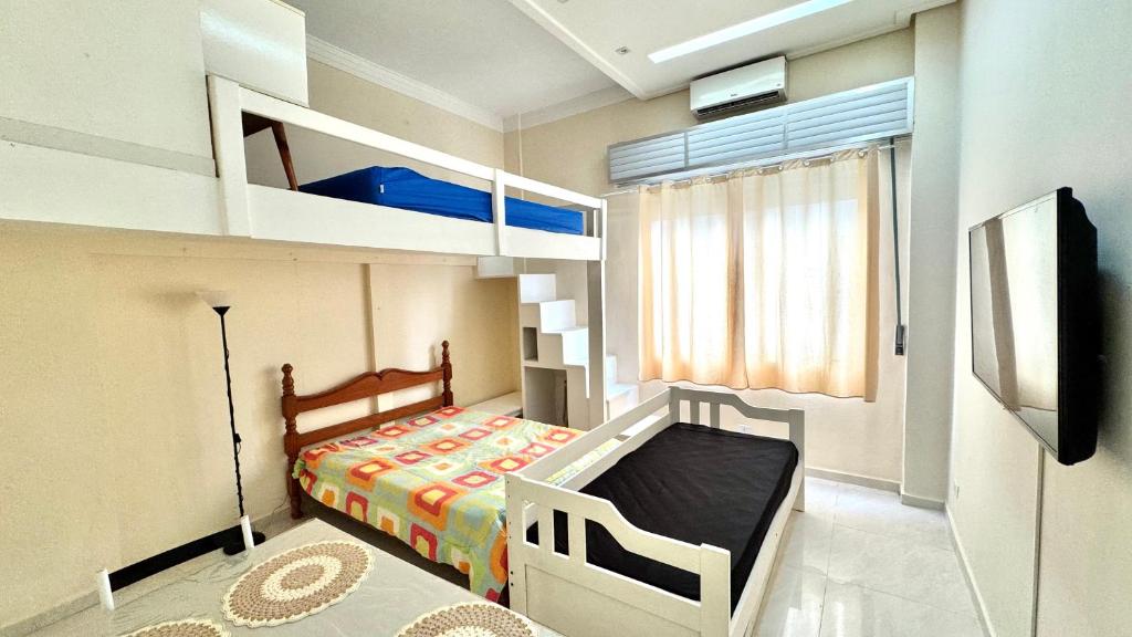 a small bedroom with a bunk bed and a television at Studio 102 Pitangueiras no térreo - ar condicionado - na quadra da praia! in Guarujá