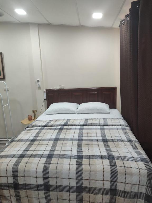 a bed in a room with a plaid blanket on it at Estancia WLC in Ayutuxtepeque