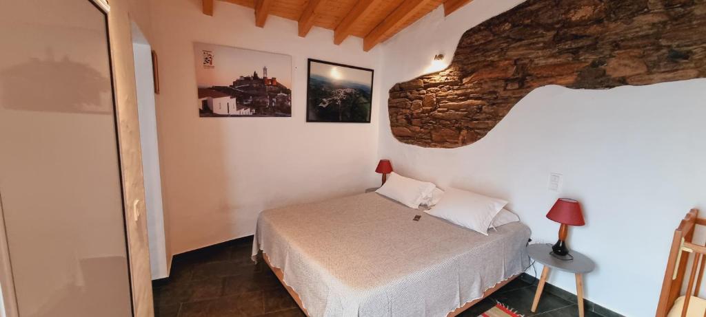 a bedroom with a bed and a stone wall at Charme de Monsaraz in Monsaraz