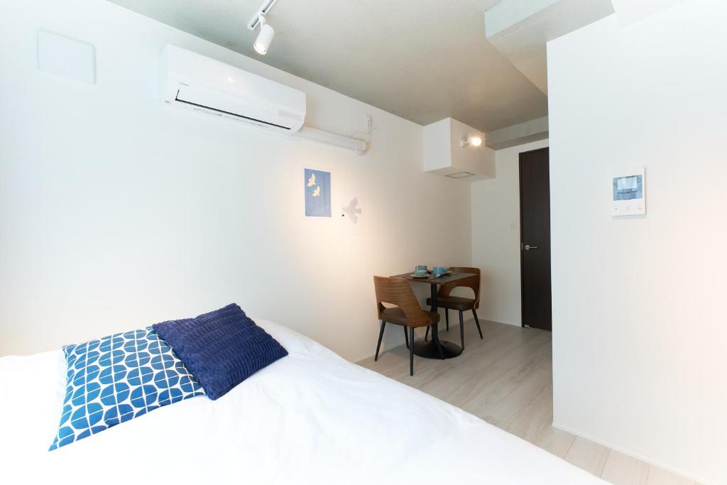 ein Schlafzimmer mit einem weißen Bett und einem Tisch in der Unterkunft Bellie Sangenjaya by Tranova in Tokio