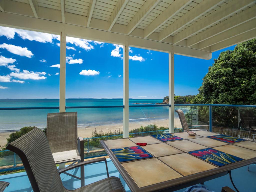 une salle à manger avec vue sur la plage dans l'établissement By the Bay Beachfront Apartments, à Mangonui