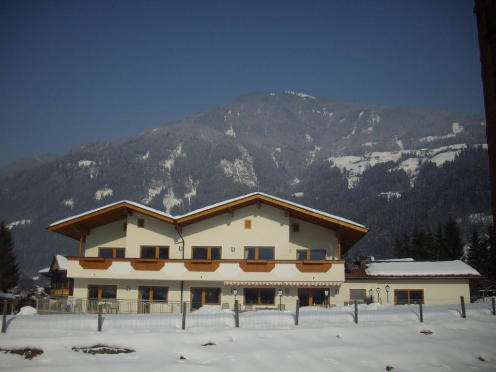 un bâtiment dans la neige avec une montagne en arrière-plan dans l'établissement Ferienhaus Zillertal, à Stumm