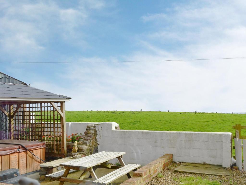 einen Picknicktisch und einen Zaun mit einem Feld im Hintergrund in der Unterkunft Old Low Farm Cottage in Aldbrough