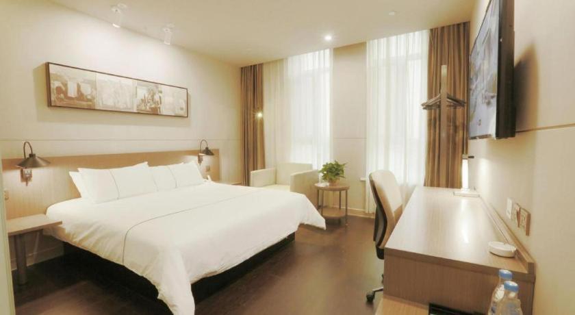 a hotel room with a large white bed and a desk at Jinjiang Inn Select Heze Wanxiang Plaza Guiling Road in Zhaolou