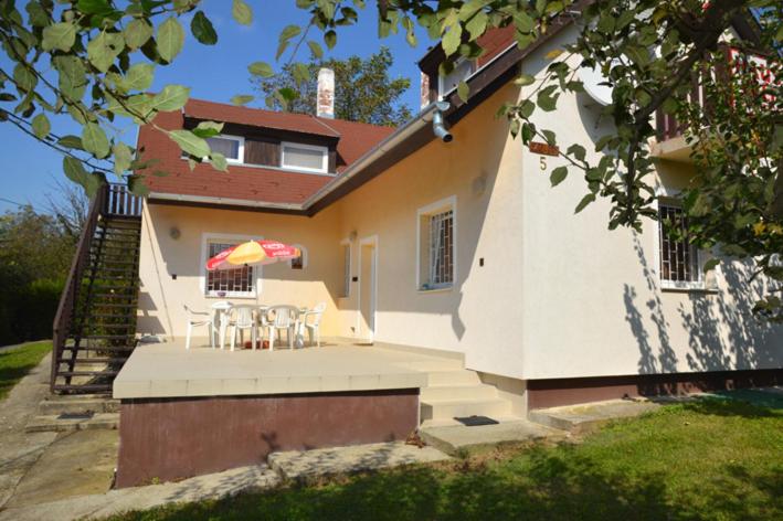 ein Haus mit einer Terrasse mit einem Tisch und einem Sonnenschirm in der Unterkunft Haus Pelso in Gyenesdiás