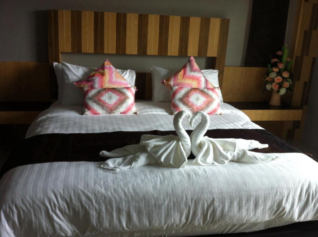 a bedroom with two beds with towels forming a heart at Hobby Hotel in Uttaradit