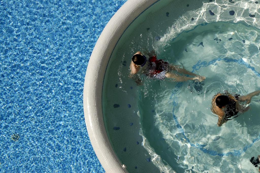 two people swimming in a swimming pool at Hotel Croce Di Malta in Lignano Sabbiadoro