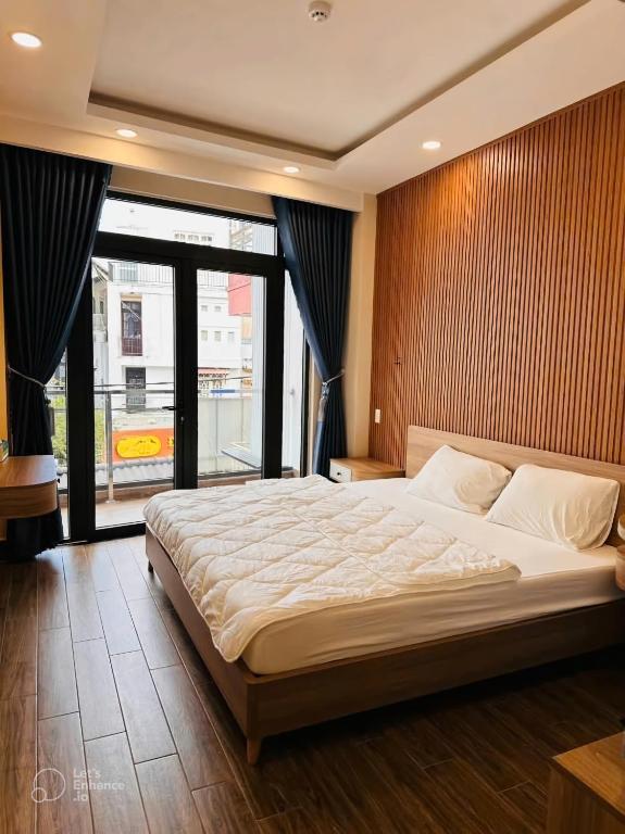 a bedroom with a large bed and a large window at Khách Sạn The Pine Scent in Da Lat