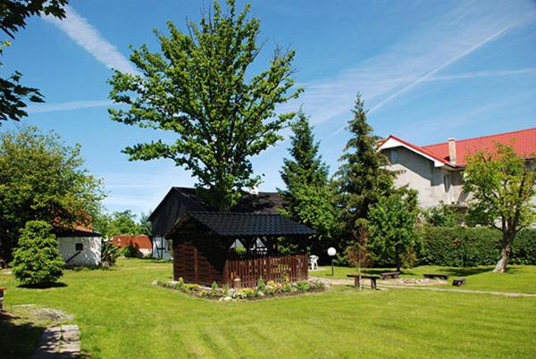 a building in a yard with a bench and a tree at Nocleg pod Dębem in Gorzebądz