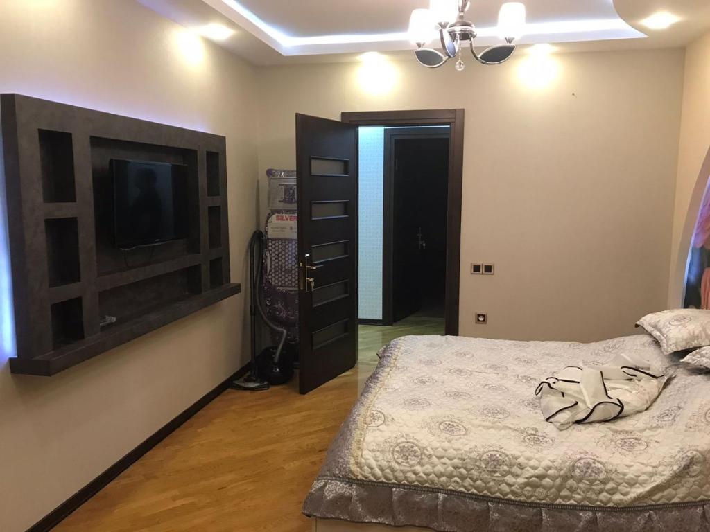 a bedroom with a bed and a dresser and a television at Хорошем месте находится, улица Иззет Небиев 6-22 in Baku