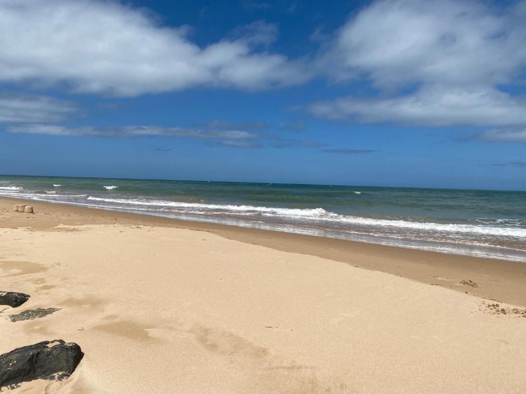 une plage de sable avec l'océan en arrière-plan dans l'établissement Appartement 2 chambres et cuisine VIERVILLE-SUR-MER,plage du Débarquement, à Vierville-sur-Mer