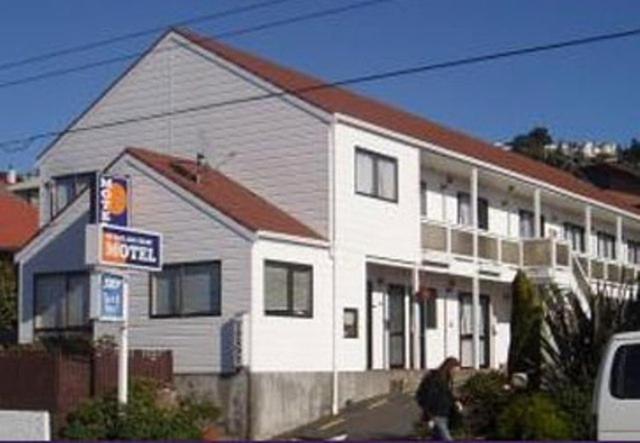 un hombre está caminando por una casa blanca en 88 Wallace Court Motel, en Wellington