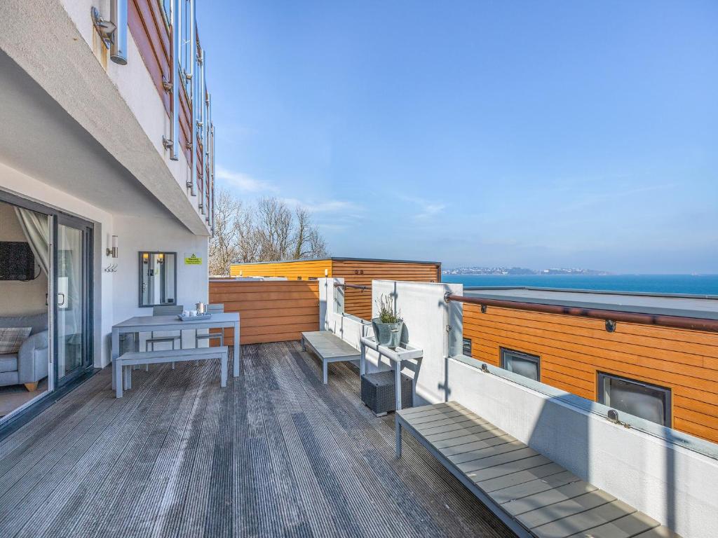 einen Balkon mit Bänken und einem Tisch auf einem Gebäude in der Unterkunft 5 Curlew, The Cove in Brixham