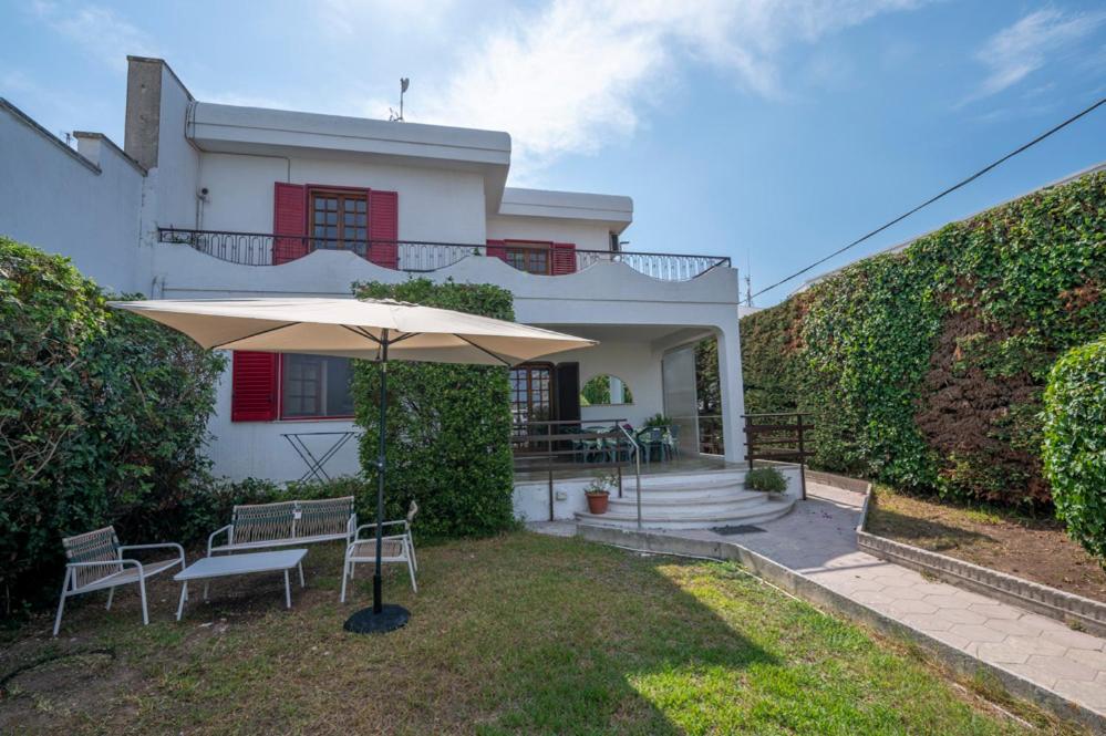una casa bianca con tavolo e ombrellone di Retreat dell'Orso - Villa per Vacanze in centro - Frontemare a Torre dell'Orso