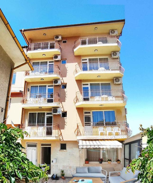 a tall building with balconies and tables in front of it at Villa Nasko Chaushev in Nesebar
