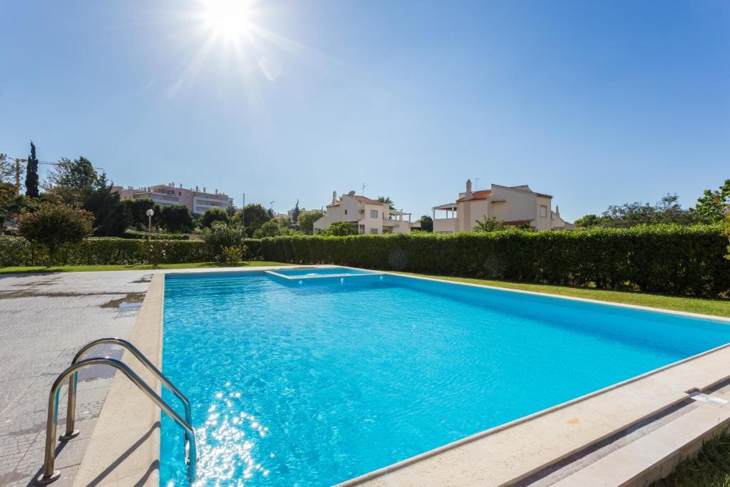 uma piscina numa villa com água azul em Edificio Sol Mr Sponsor Apartment em Portimão