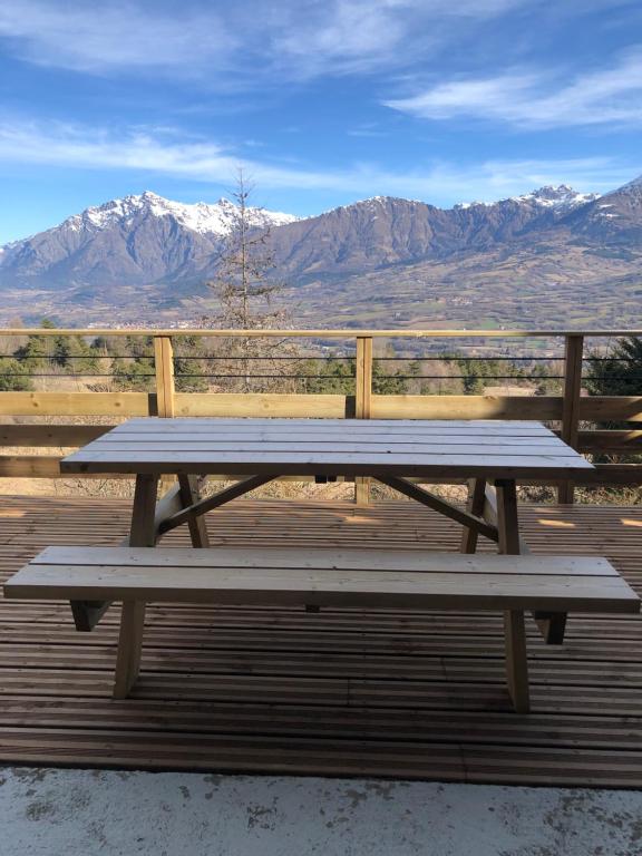 une table de pique-nique sur une terrasse avec des montagnes en arrière-plan dans l'établissement Le Chamois 2, à Laye