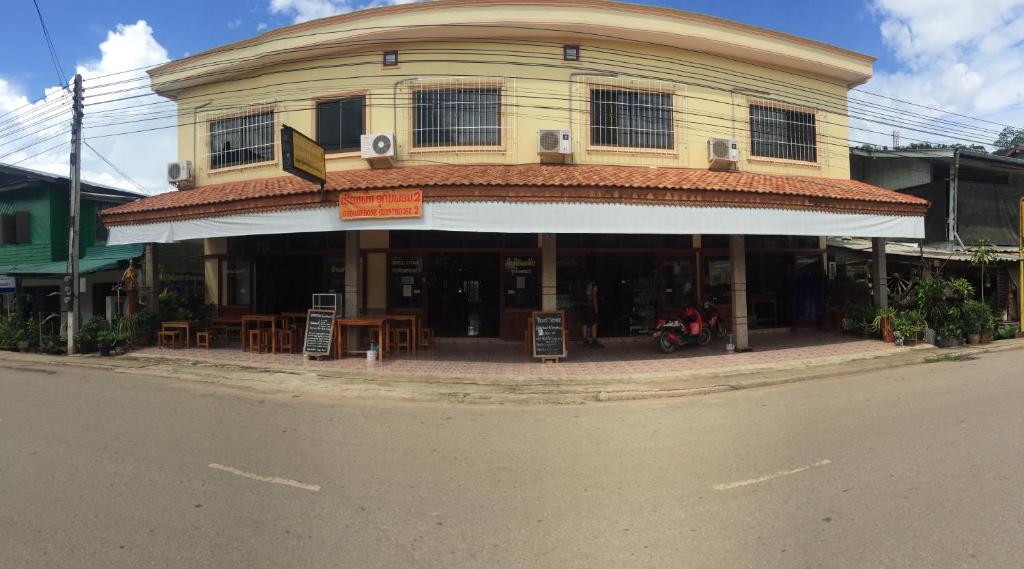 a building on the corner of a street with a restaurant at Oudomphone Guesthouse 2 in Ban Houayxay