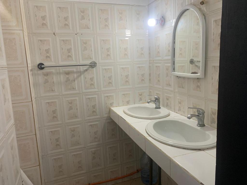 a bathroom with two sinks and a mirror at Joli appartement a saly pres de barracuda in Saly Portudal
