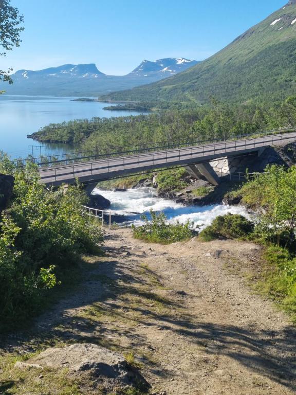 a bridge over a river with mountains in the background at Micke o Ritas stuga in Björkliden