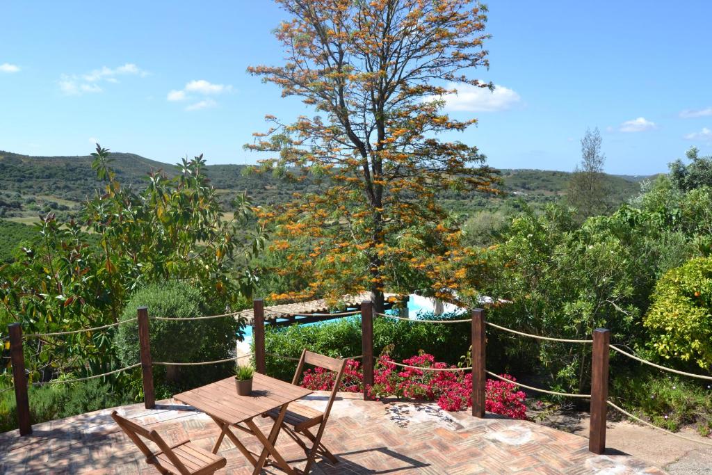 um pátio com uma mesa, cadeiras e uma árvore em Vale Fuzeiros Nature Guest House em Vale Fuzeiros