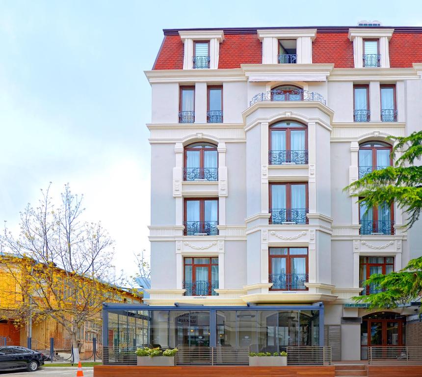 un edificio blanco con techo rojo en City Avenue Hotel, en Tiflis