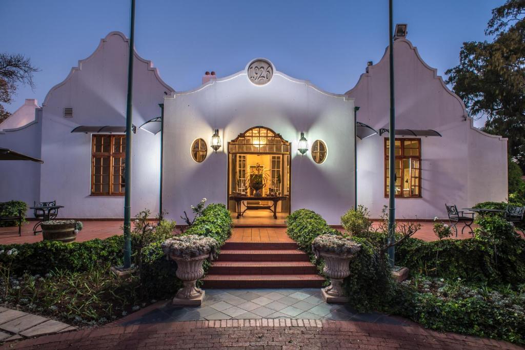 a white house with stairs leading to the front door at River Meadow Manor in Centurion