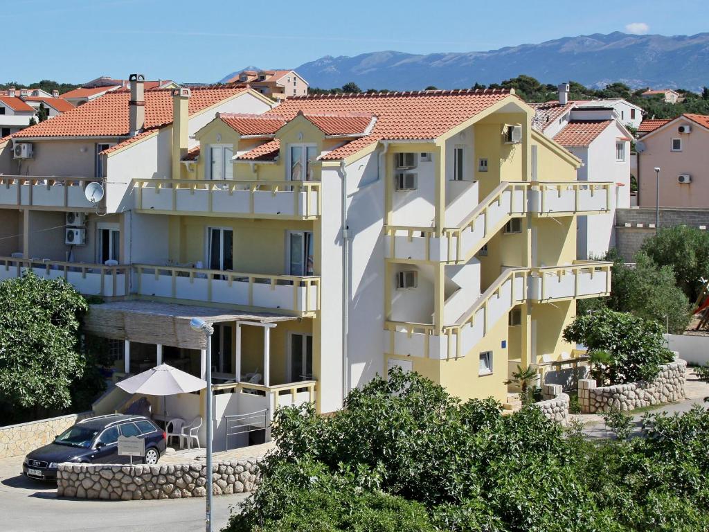 un bâtiment jaune avec une voiture garée devant lui dans l'établissement Apartments Jasmina, à Novalja