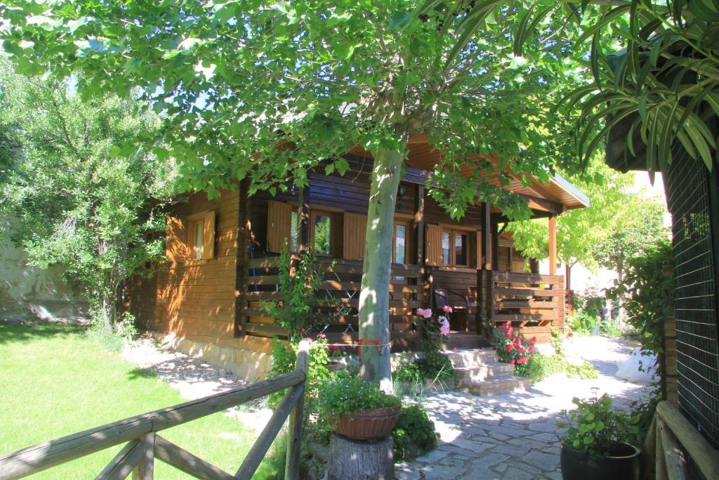 una casa de madera con un árbol y una valla en Cabañas los Pinos Arroyo Frio, en Arroyo Frío