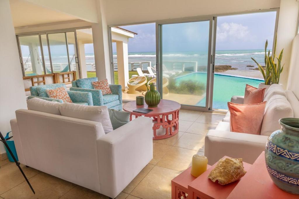 PalenqueにあるCaribbean Paradise Beachfront Villaの白い家具付きのリビングルームが備わり、海の景色を望めます。
