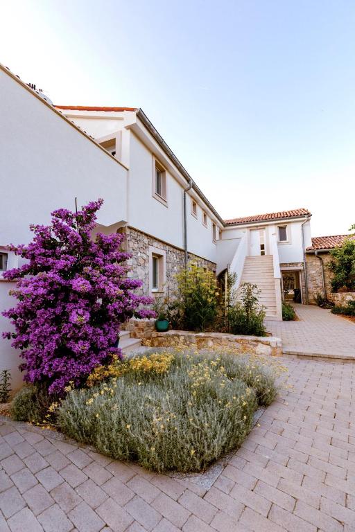 a house with a purple tree in front of it at Citadela Veli Lošinj in Veli Lošinj