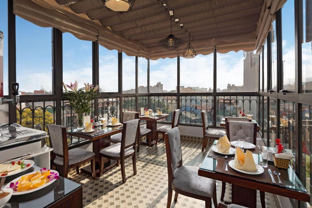 a restaurant with tables and chairs and windows at Golden Moon Suite Hotel in Hanoi