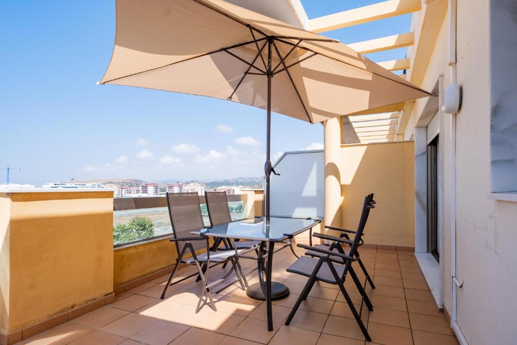 a table and chairs on a balcony with an umbrella at Apartamentos Proamar in Torre del Mar