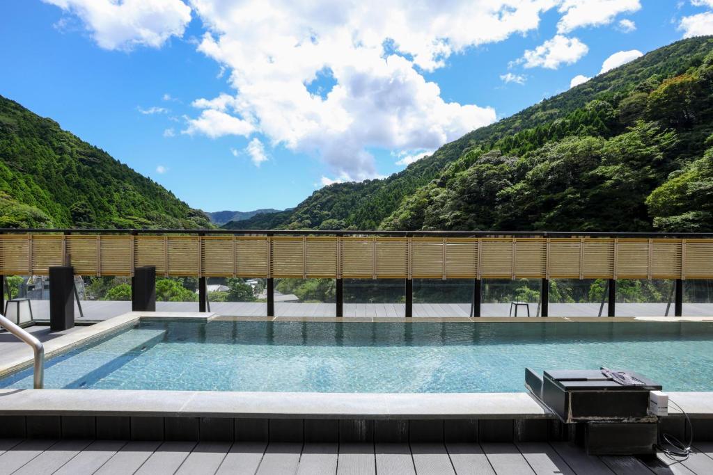 a swimming pool on a deck with mountains in the background at Oku Yugawara SANSUIROU in Yugawara