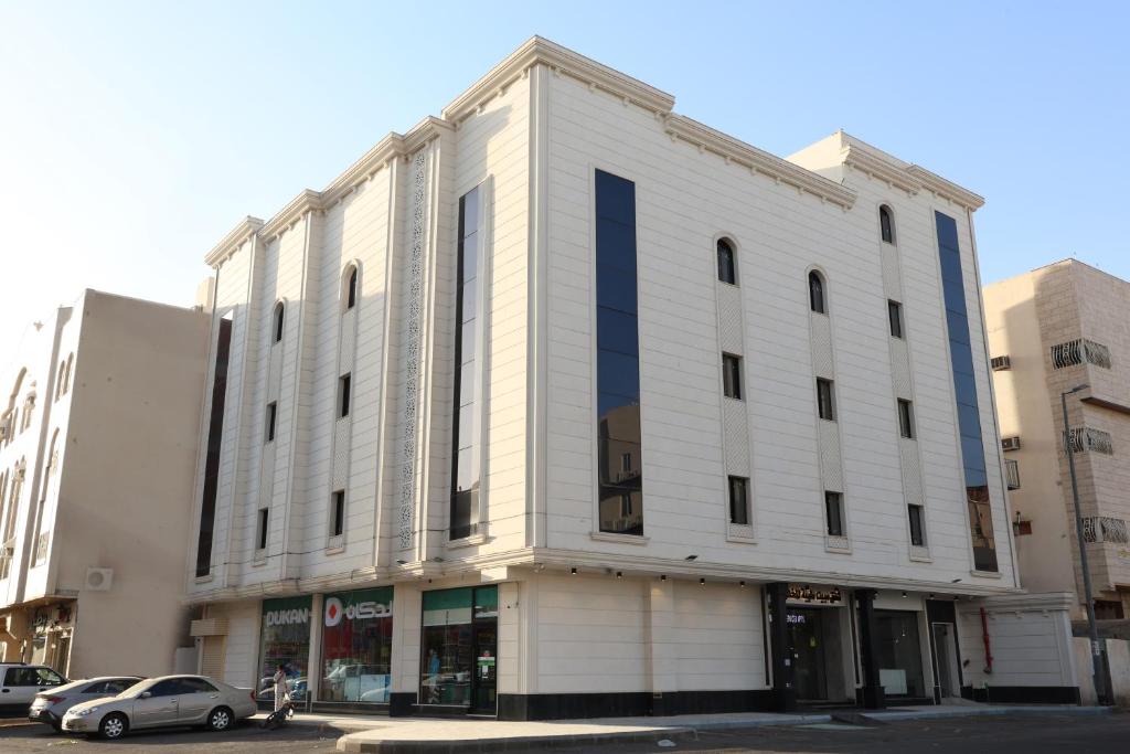 a white building with a car parked in front of it at شقق مبيت طيبة المخدومة-Mabeet Taiba- in Al Madinah