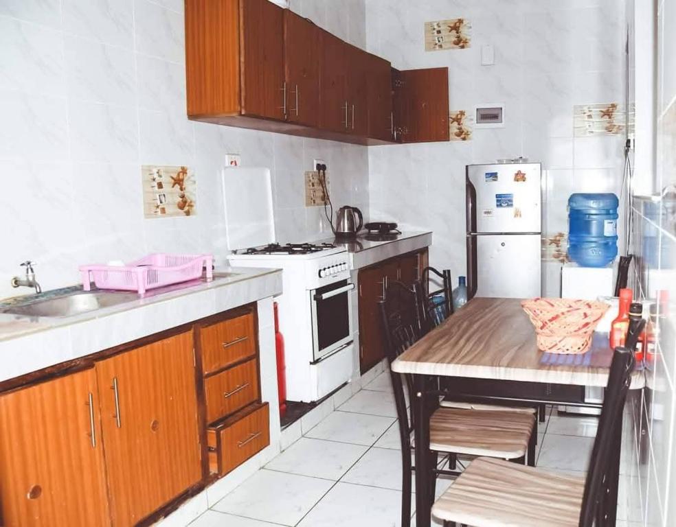 a kitchen with a table and a stove and a refrigerator at HawiHomes in Mombasa