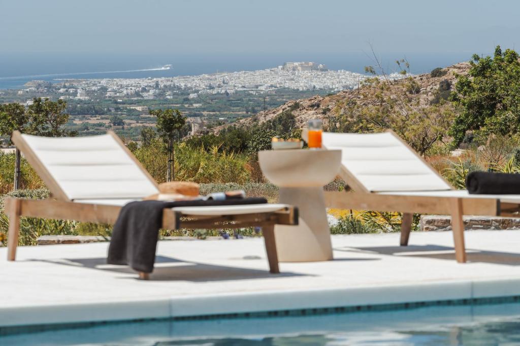 a pool with two lounge chairs and a table next to it at Villa THÉA - Private pool, Stunning Sea views in Plaka