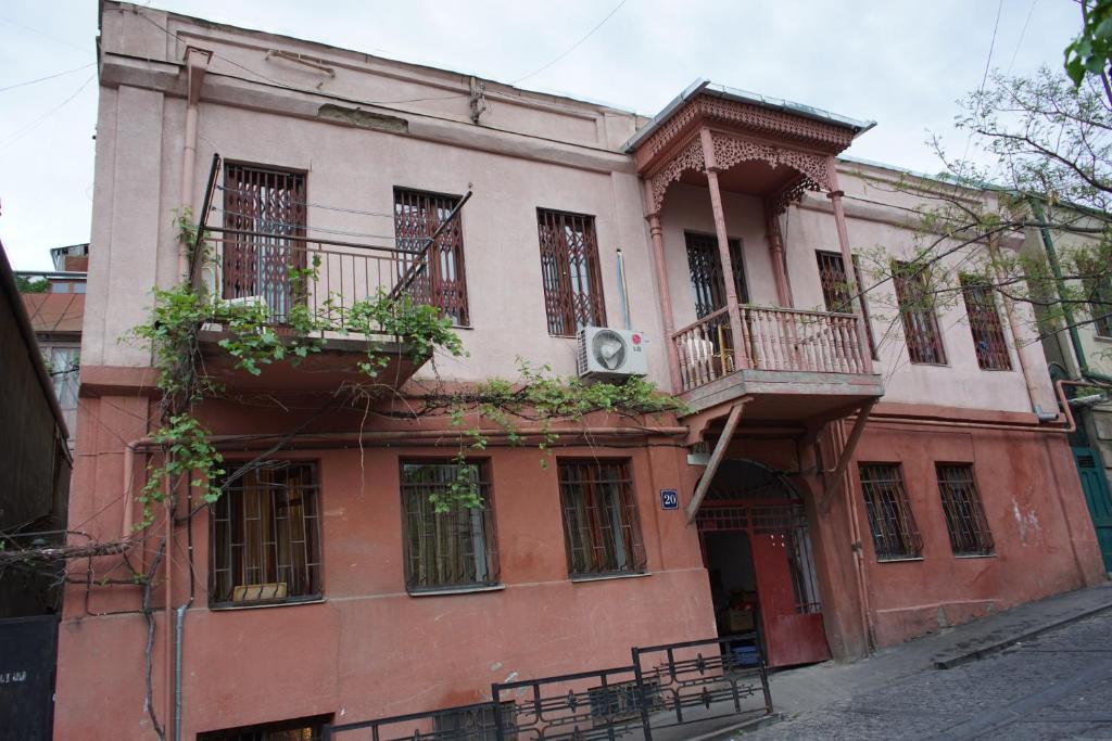 an old red building with balconies on a street at Guest House 20 in Tbilisi City