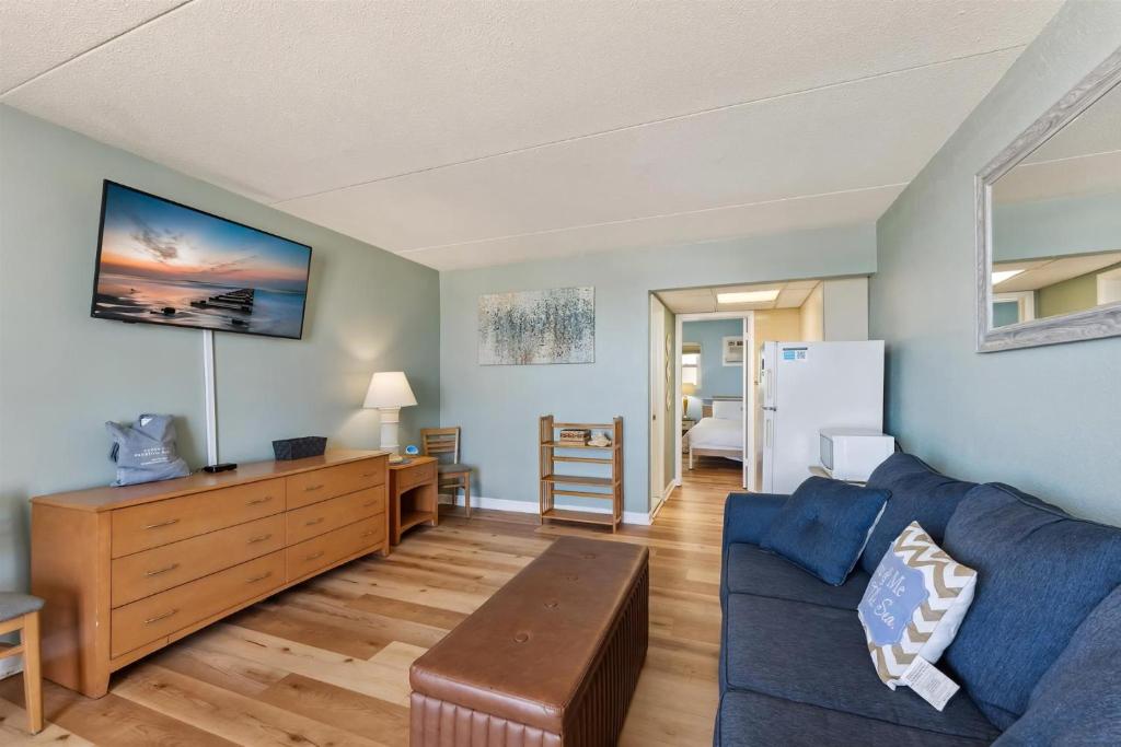 Una sala de estar con un sofá azul y una mesa. en 6201 Ocean Ave, Unit 406 - The Nassau Inn, en Wildwood